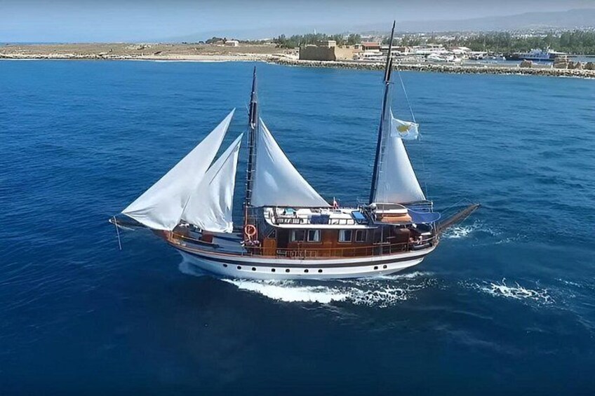 A sailing yacht on the water with a clear sky and distant land. 1