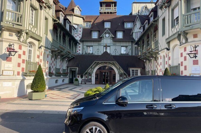 A black van parked in front of a historic building with a checkered facade and a clock tower. 2