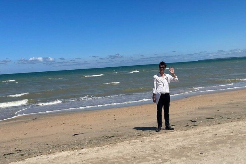 A person standing on a sandy beach with the ocean in the background. 4