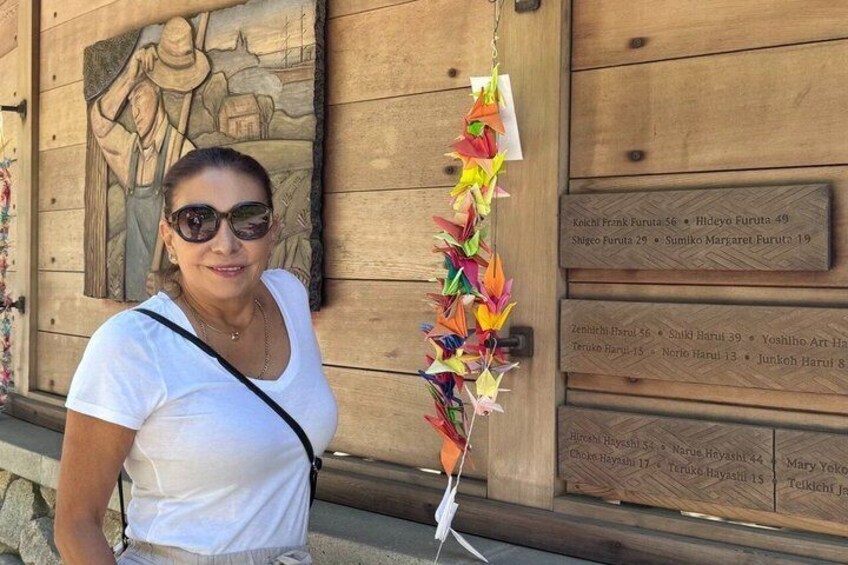 A person standing in front of a wooden wall with a relief sculpture and a list of names. 5