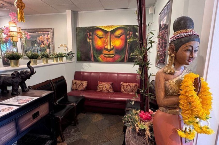 A room with a red sofa, a Buddha statue, and a painting of a Buddha's face. 4