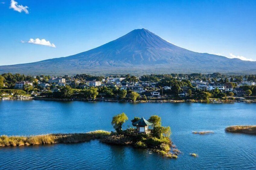 A lake with a small island, a mountain in the background, and a town across the water. 4