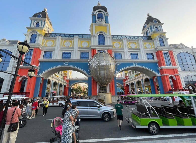 A colorful building with a large spherical structure in front, a busy street, and a green bus. 5