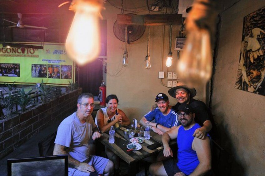 A group of people sitting at a table in a restaurant with a sign that reads 'GONCOTO' in the background. 2