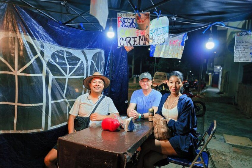 A group of people sitting at a table with a tent in the background. 3