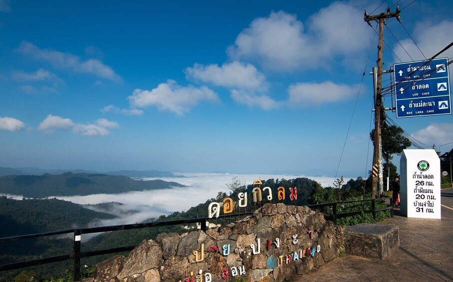 A scenic viewpoint with a clear sky, a rocky foreground, and a distant forested landscape. 5