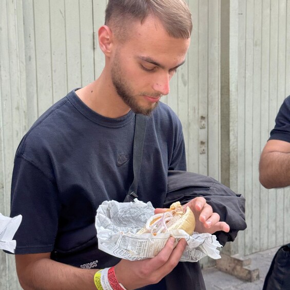 A person holding a sandwich wrapped in newspaper. 2
