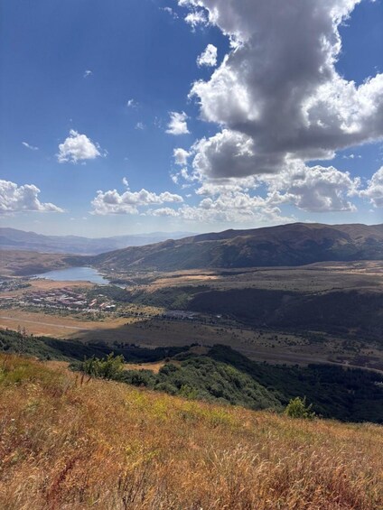 A valley with a lake, surrounded by hills and a clear sky. 5