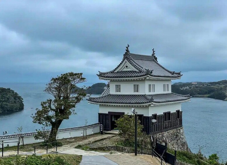 A traditional Japanese castle with a view of the sea and hills in the background. 4