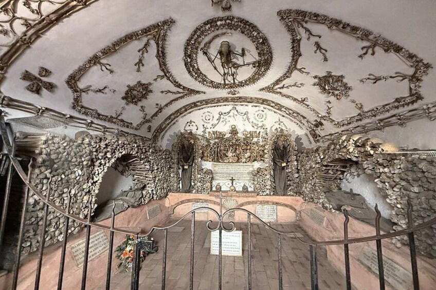 An ornate chapel interior with intricate ceiling artwork, a central altar, and stone walls. 1