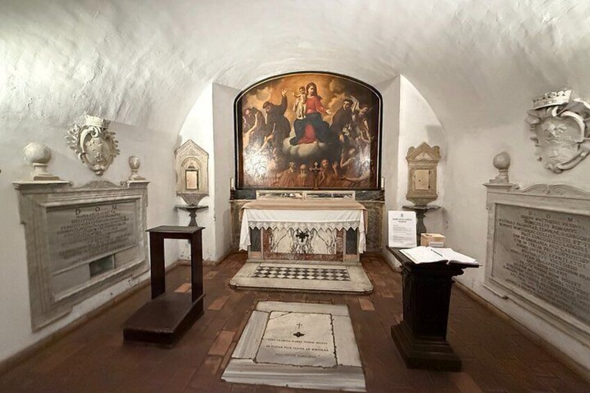 A chapel interior with a religious painting, a chessboard, and two plaques on the walls. 3