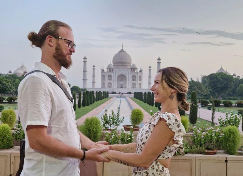 Pariskunta kävelee käsi kädessä, ja taustalla näkyy Taj Mahal. 1