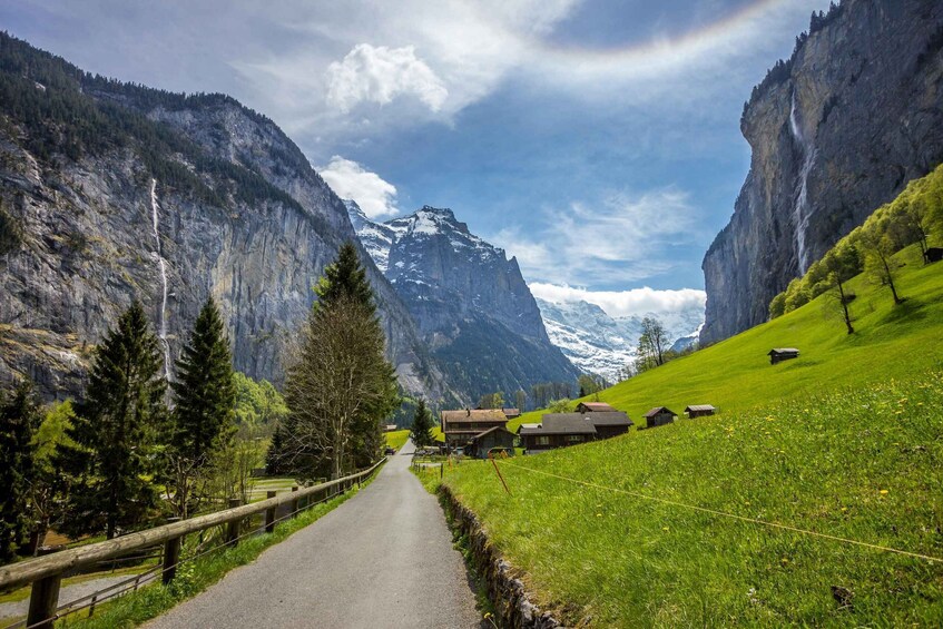 A mountain road with houses, a wooden fence, and a waterfall. 3
