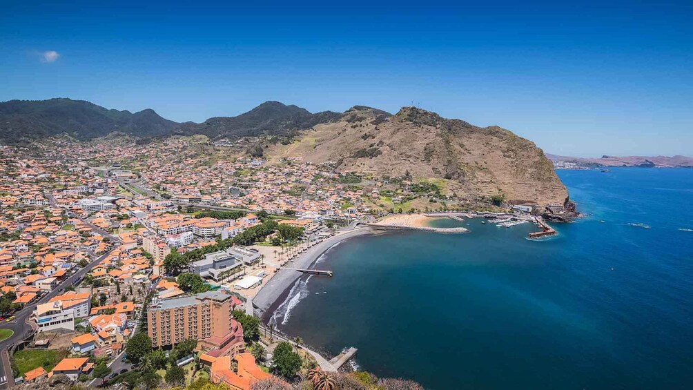 A coastal town with a beach, buildings, and mountains in the background. 5