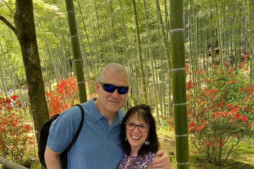 Una pareja en un bosque de bambú con plantas de flores rojas. 5