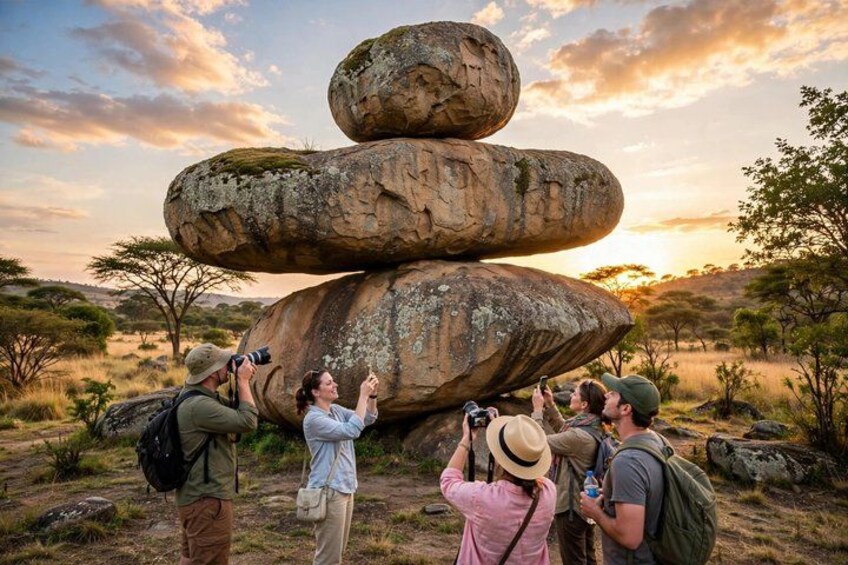 A group of people taking photographs of a large rock formation. 1