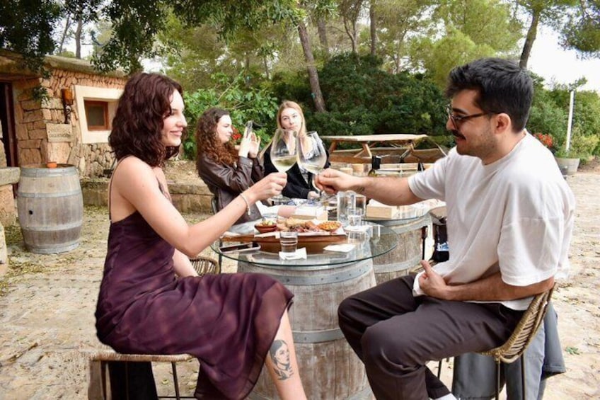 A group of people dining outdoors at a round table with food and drinks. 5