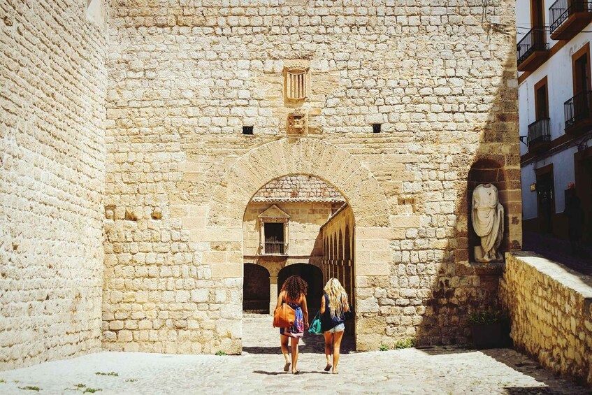 A stone building with an arched entrance and a statue on the right. 4
