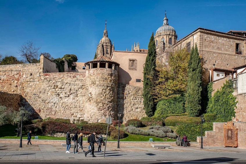 A historic stone wall, a church with a dome, and a well-maintained garden. 5