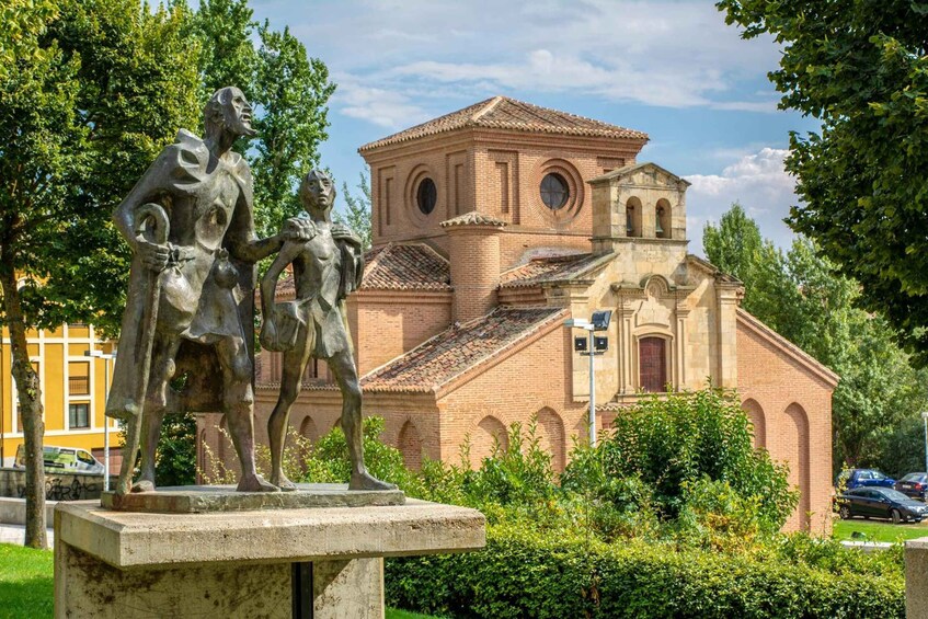 A statue of a man and woman in a park with a church in the background. 3