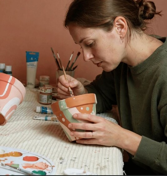 A person painting a ceramic pot with a brush. 3