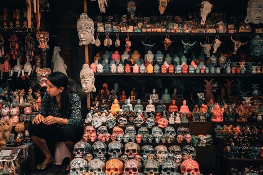 A person sitting amidst a variety of skull-shaped objects and decorative items. 3