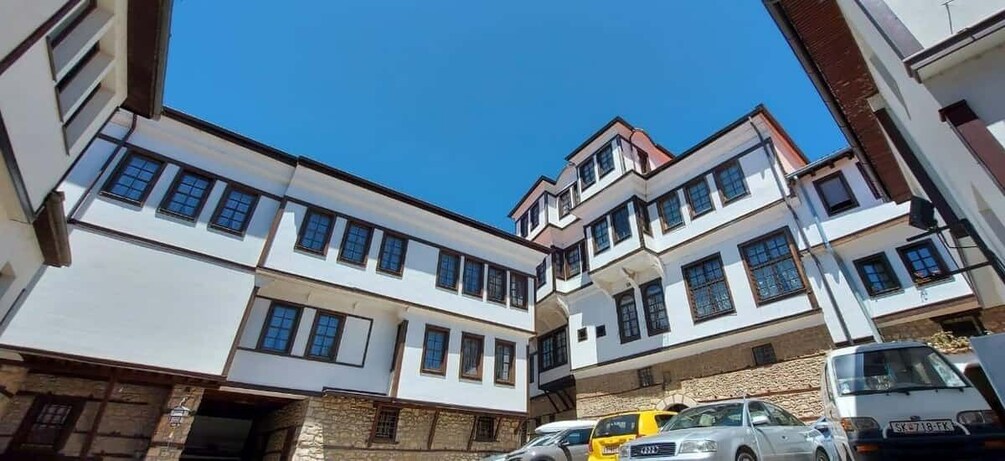 A multi-story building with a white facade and multiple windows. 5