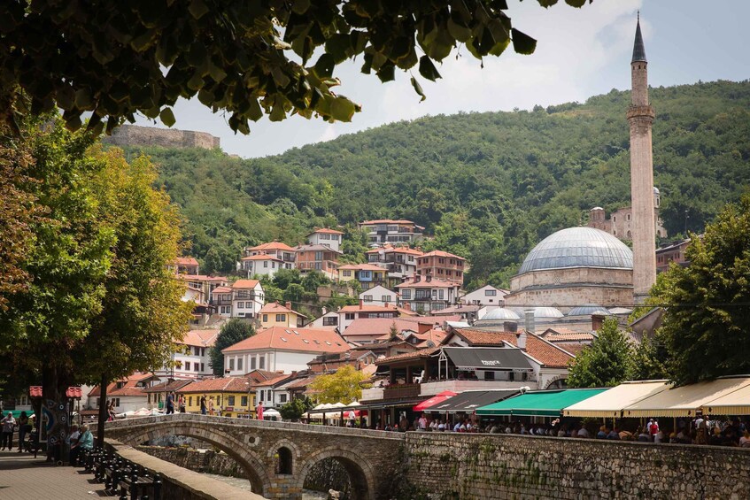 A historic town with a prominent minaret, a dome, and a stone bridge. 1