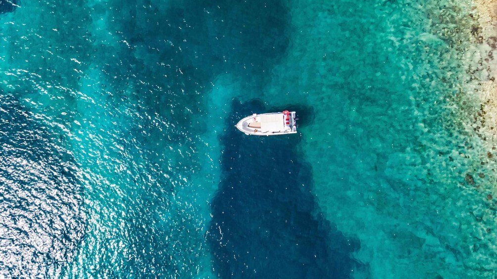 A boat anchored in clear turquoise waters with a sandy beach in the background. 2