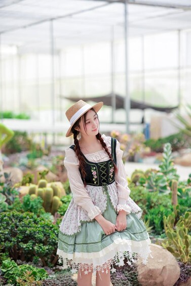 A person in traditional attire standing in a greenhouse with various plants. 3