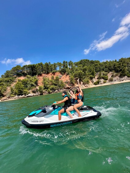 A person riding a jet ski on a body of water with a forested hillside in the background. 1