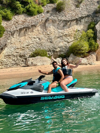 Two people on a Sea-Doo jet ski, with rocky cliffs and greenery in the background. 5