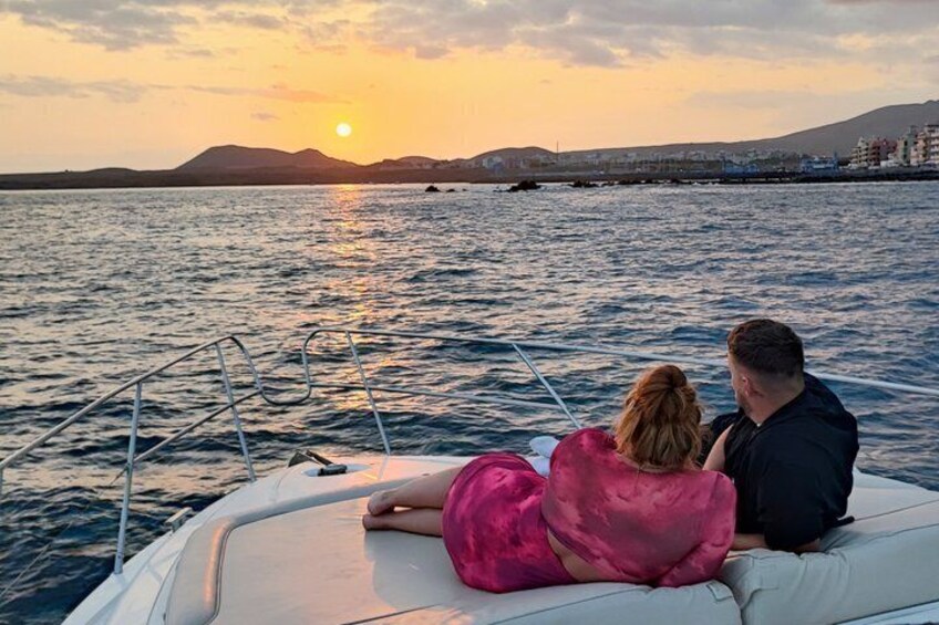 A couple on a boat at sunset with water and distant hills. 2