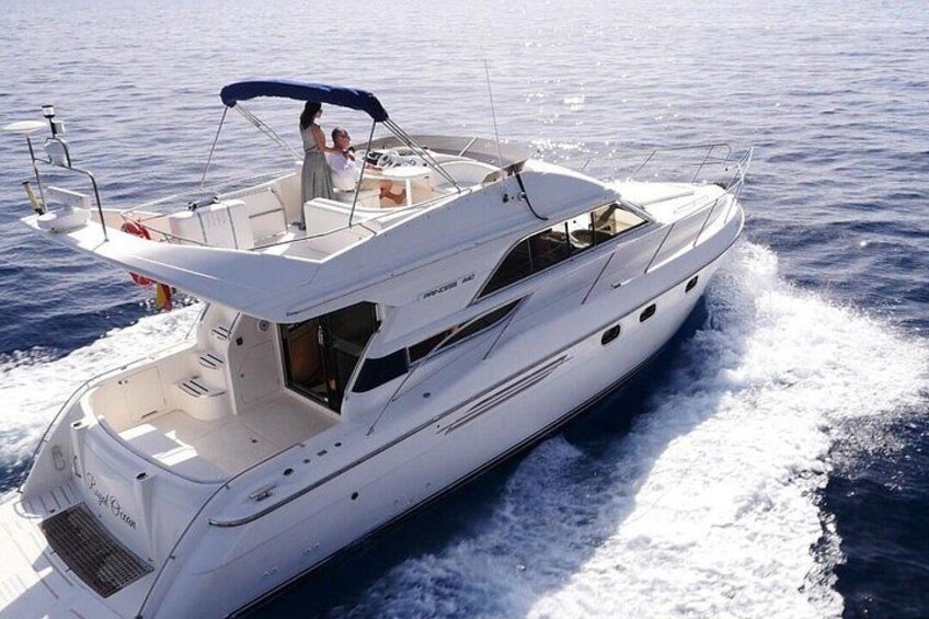 A white yacht with a covered deck, moving through calm waters. 5