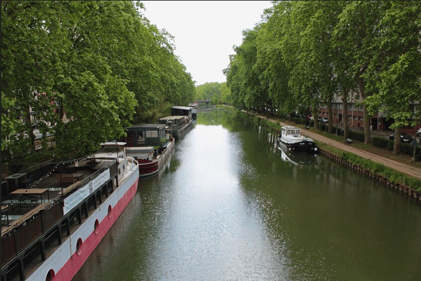 A canal lined with trees and boats, including a red and white ferry. 2