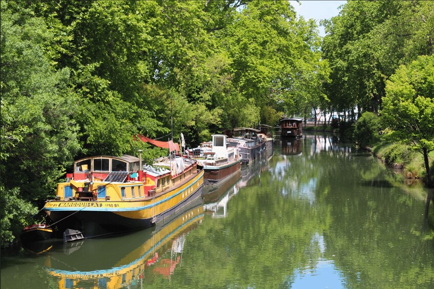 A river with boats docked along the banks, surrounded by lush green trees. 4