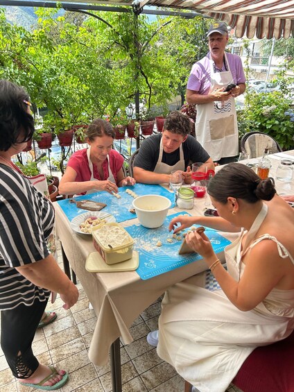 People baking cookies outdoors with a table covered in baking supplies. 1