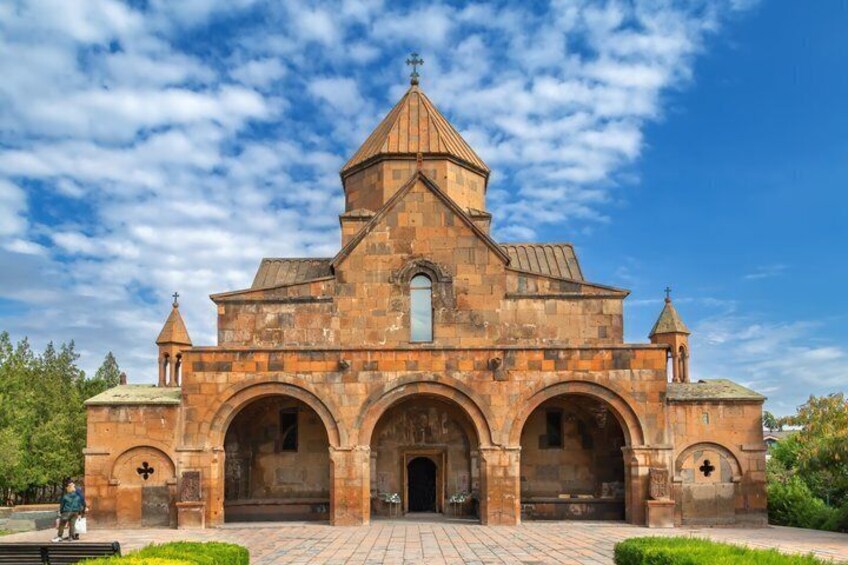 A stone church with a central dome, arched entrance, and two smaller towers. 3