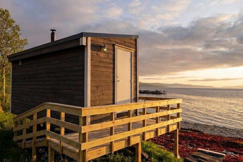 A wooden cabin with a deck overlooking a body of water. 1