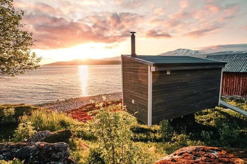 A wooden cabin by a lake with a sunset in the background. 5