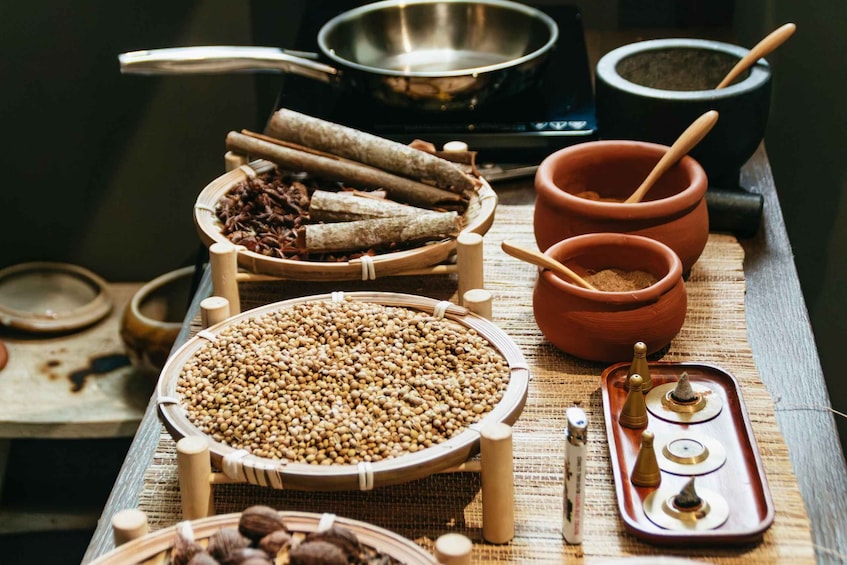 A traditional cooking setup with various spices, a mortar and pestle, and cooking utensils. 5
