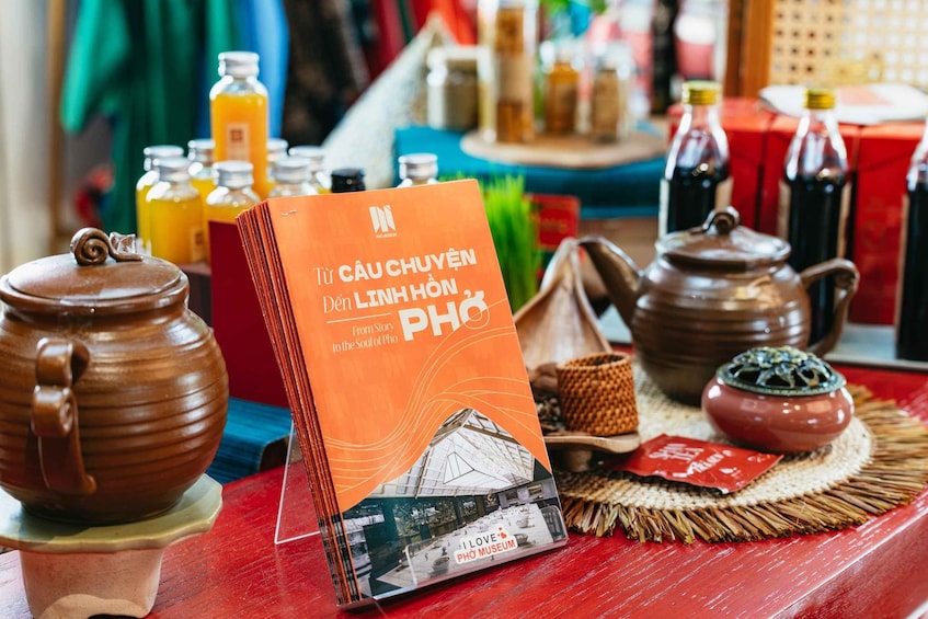 A book titled 'Tứ Câu Huyên' by Linh Hòn PHO, placed on a table with traditional Vietnamese tea sets and other cultural items. 2