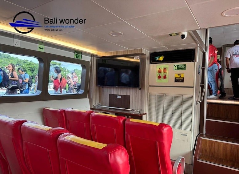 A train interior with red seats, a TV screen, and a window displaying people outside. 3