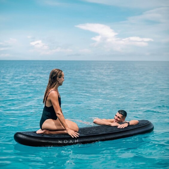 Two people on a floating platform in a body of water with a clear sky. 2