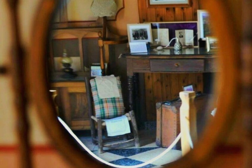 A wooden desk with a plaid chair, a lamp, and framed pictures. 5