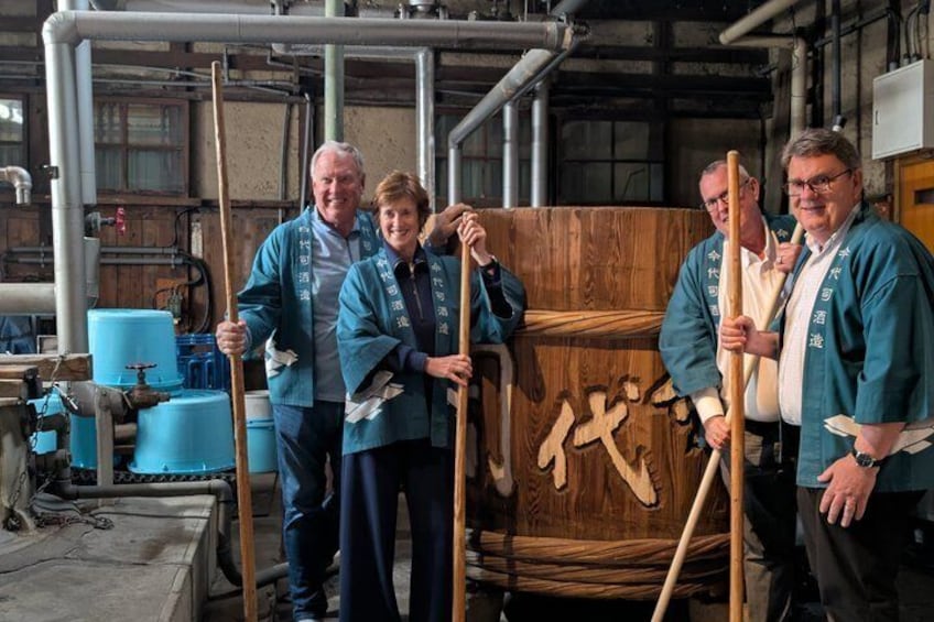 Four people in a workshop holding wooden planks and tools. 1