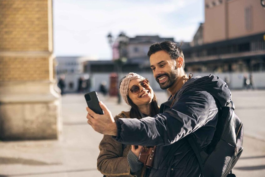 A couple taking a selfie in an urban square with buildings in the background. 4