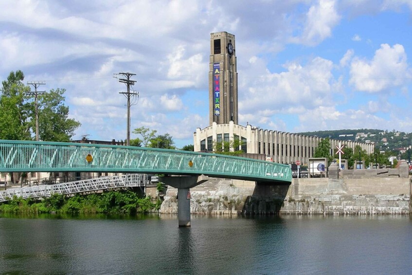 A bridge over water, a tall tower with a clock, and a distant cityscape. 5