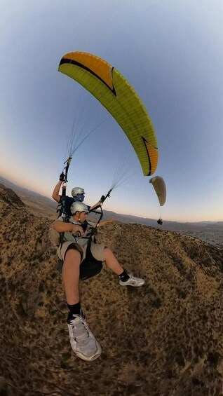 A person paragliding over a mountainous terrain. 5