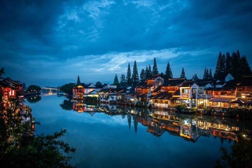 A riverside town at dusk with illuminated buildings reflecting on the water. 3